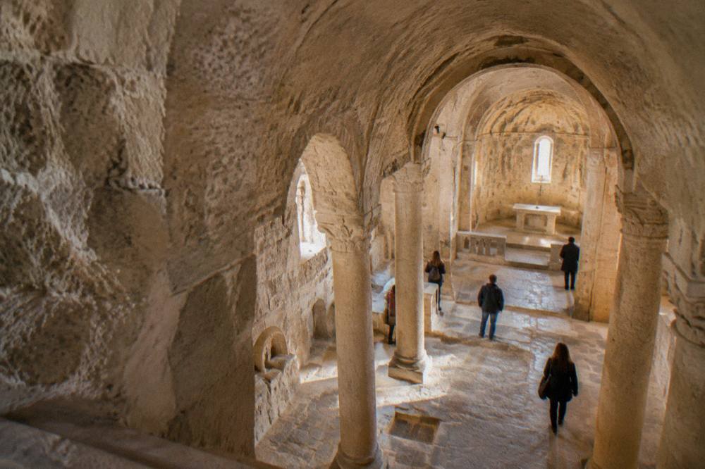 Interior of a rock-cut church in Matera with carved columns and a barrel ceiling