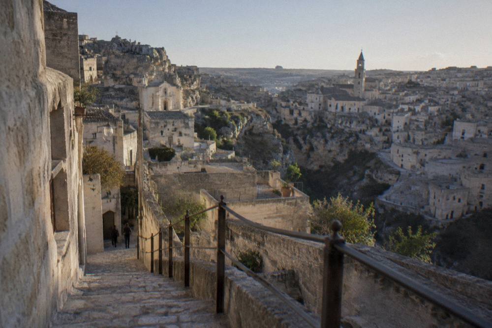 Worn stone steps and an iron railing descending a narrow Sassi lane in Matera