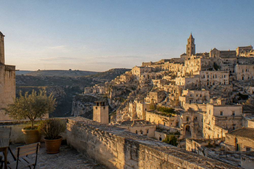 Golden evening light on the stacked stone facades of the Sassi of Matera seen from a rooftop terrace