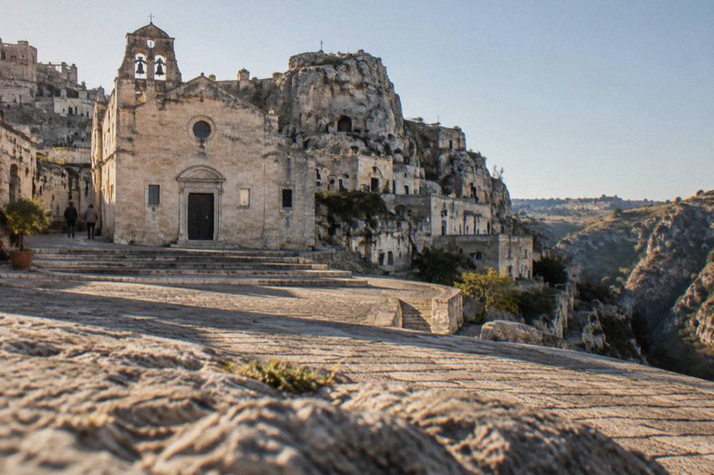 Cave dwellings built into a pale limestone cliff with stairways between stone houses