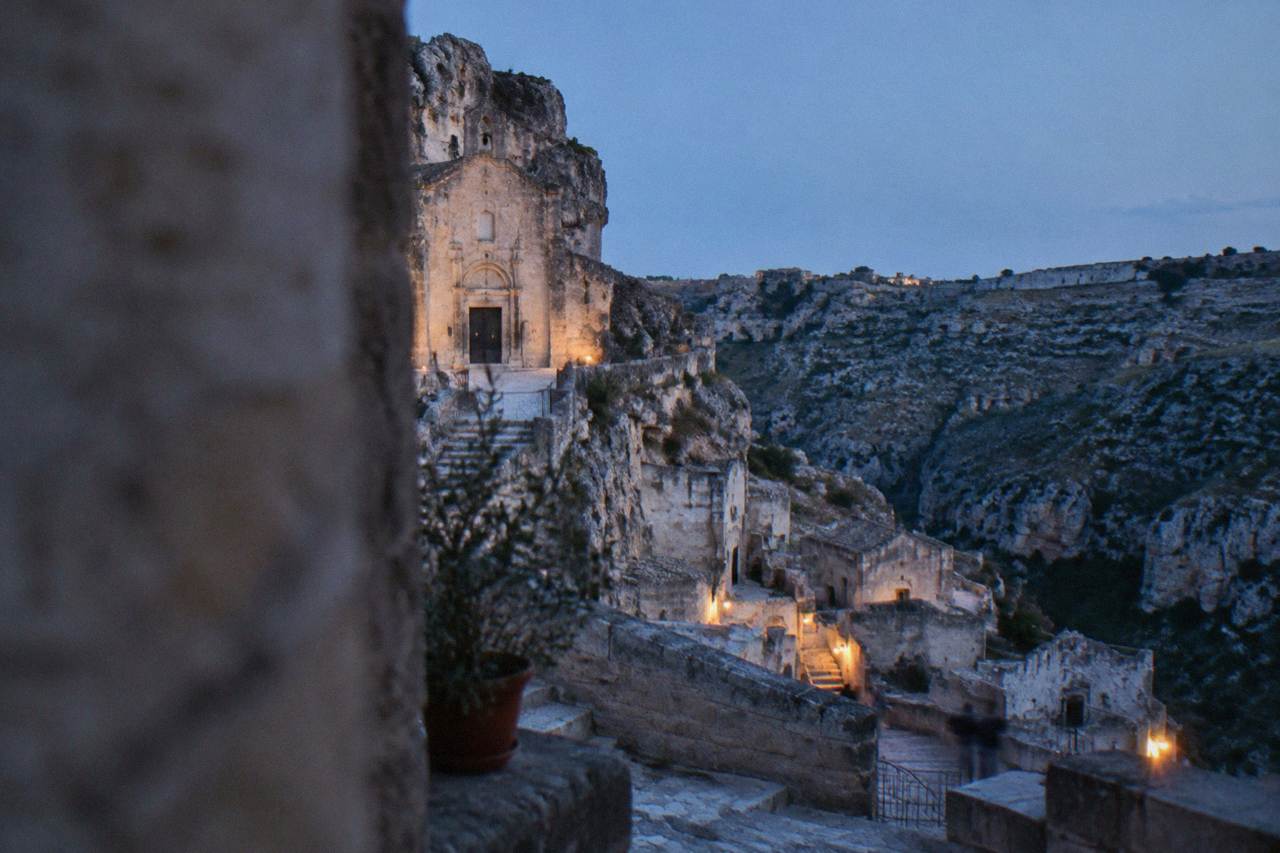 A pale rock-cut church facade on a stone spur above the cave dwellings of the Sasso Caveoso in Matera