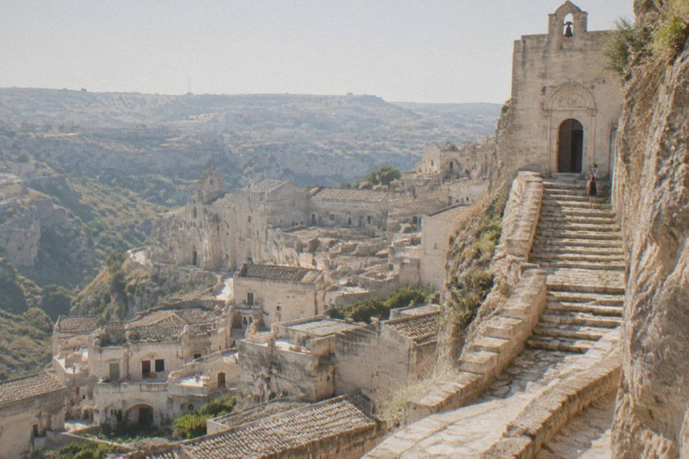 Stone steps carved into the rock leading up to a church entrance above the rooftops of Matera
