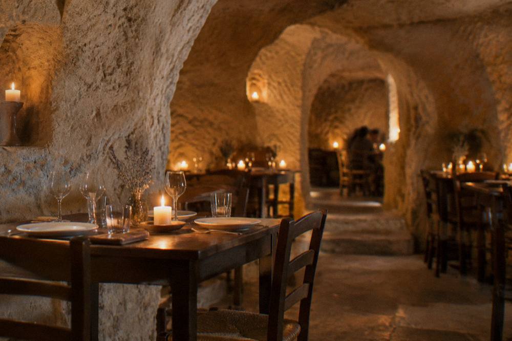 A candlelit cave restaurant interior with stone vaults and set tables
