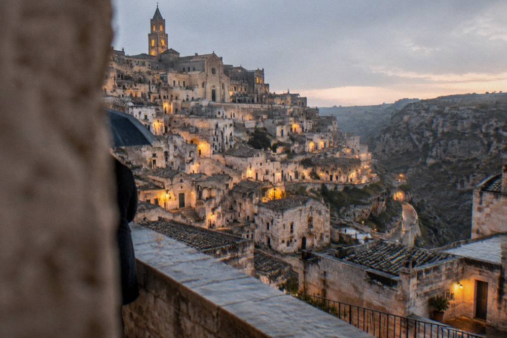 The Sassi districts illuminated at dusk seen from a terrace above the canyon