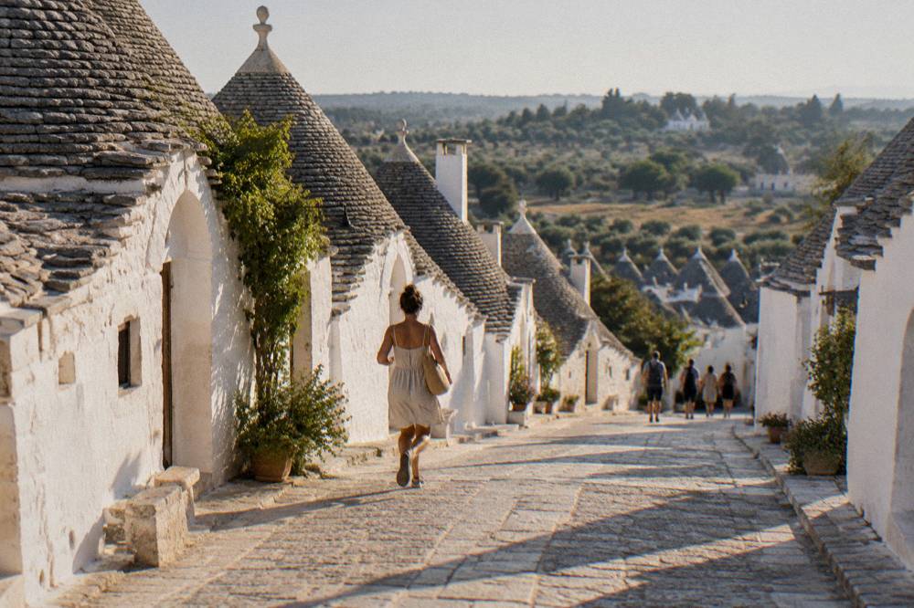 A country road in the Itria valley with scattered trulli among olive trees