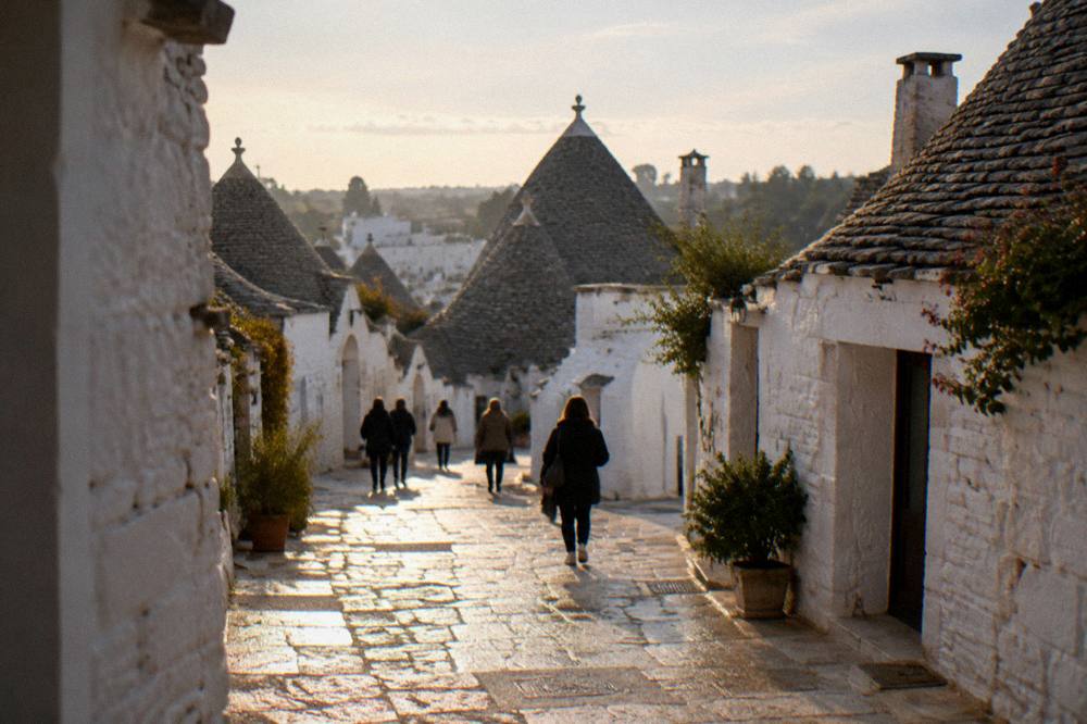A trullo street in warm evening light with a few people walking