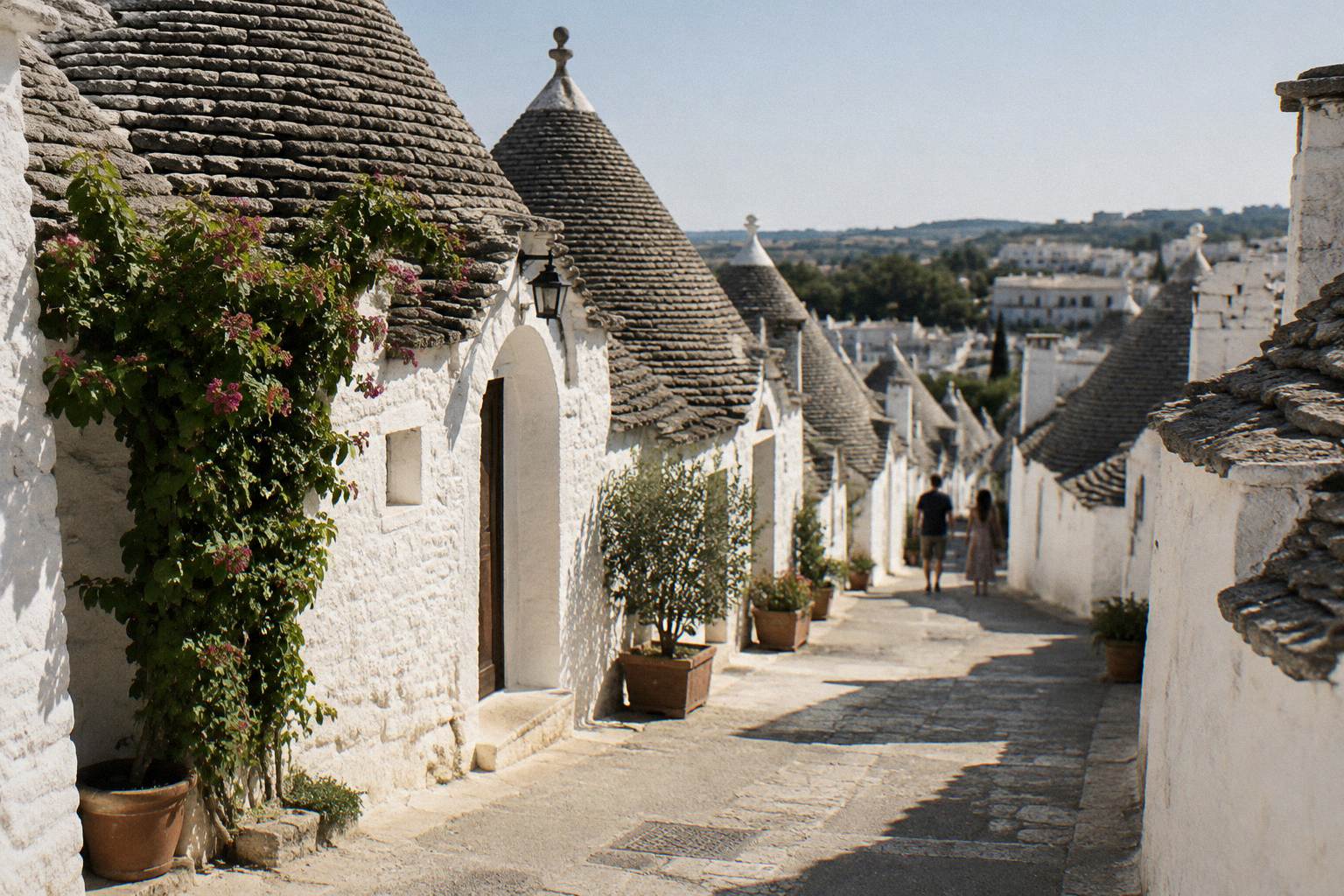 Rows of whitewashed conical-roofed trulli houses on a sunlit hillside street
