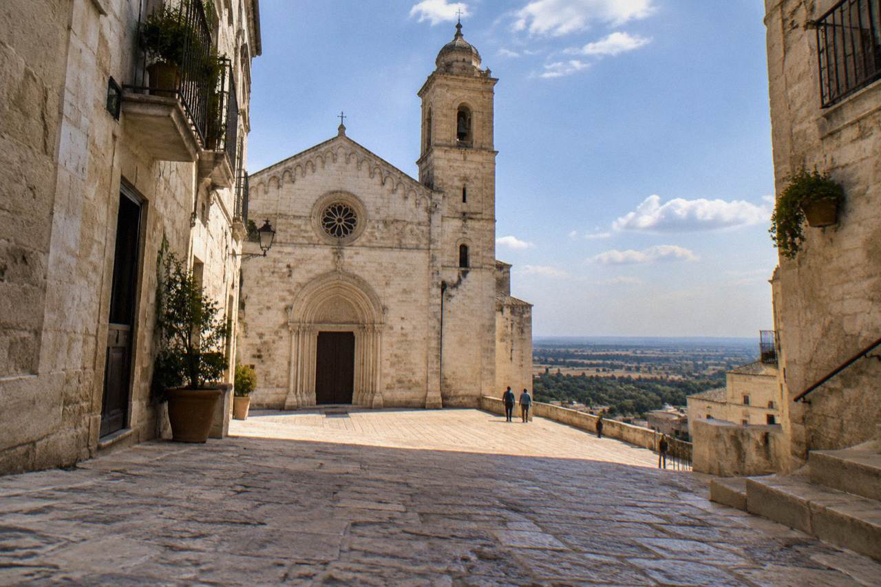 A stone street in an old southern Italian town with pale limestone buildings