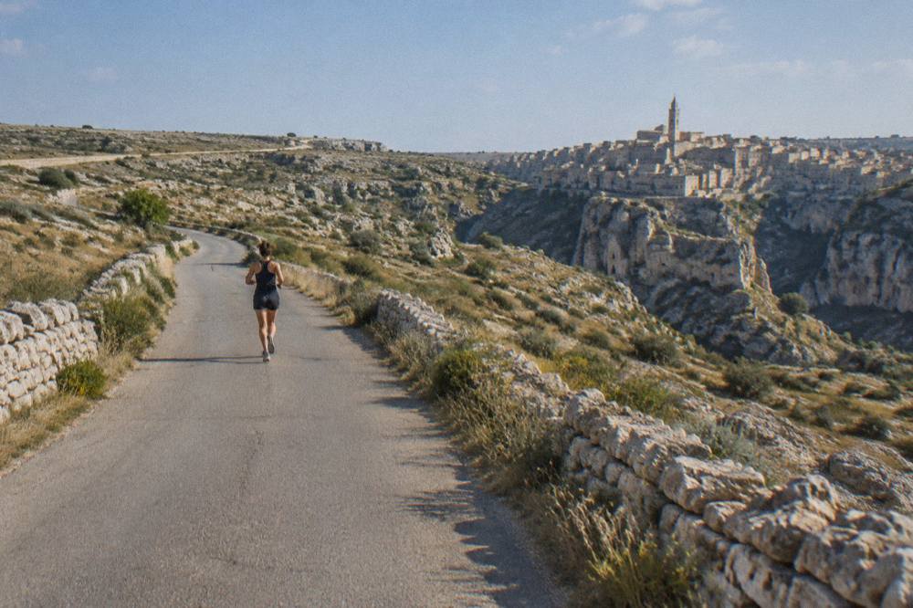 An empty country road crossing the Murgia plateau between stone walls and scrub