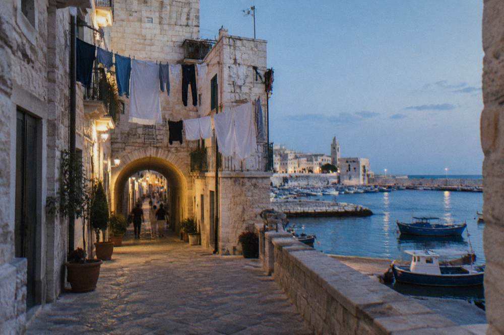 A busy old town street with washing lines strung between pale stone buildings
