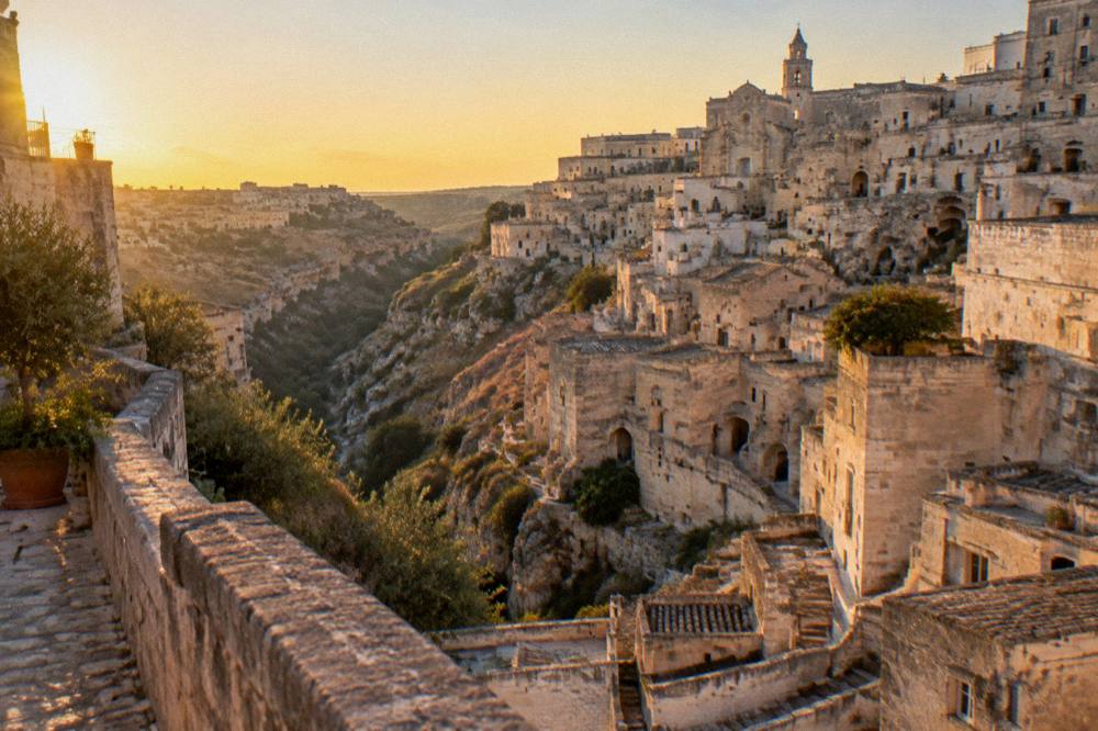 Cave dwellings and stone facades of Matera seen across a canyon at golden hour
