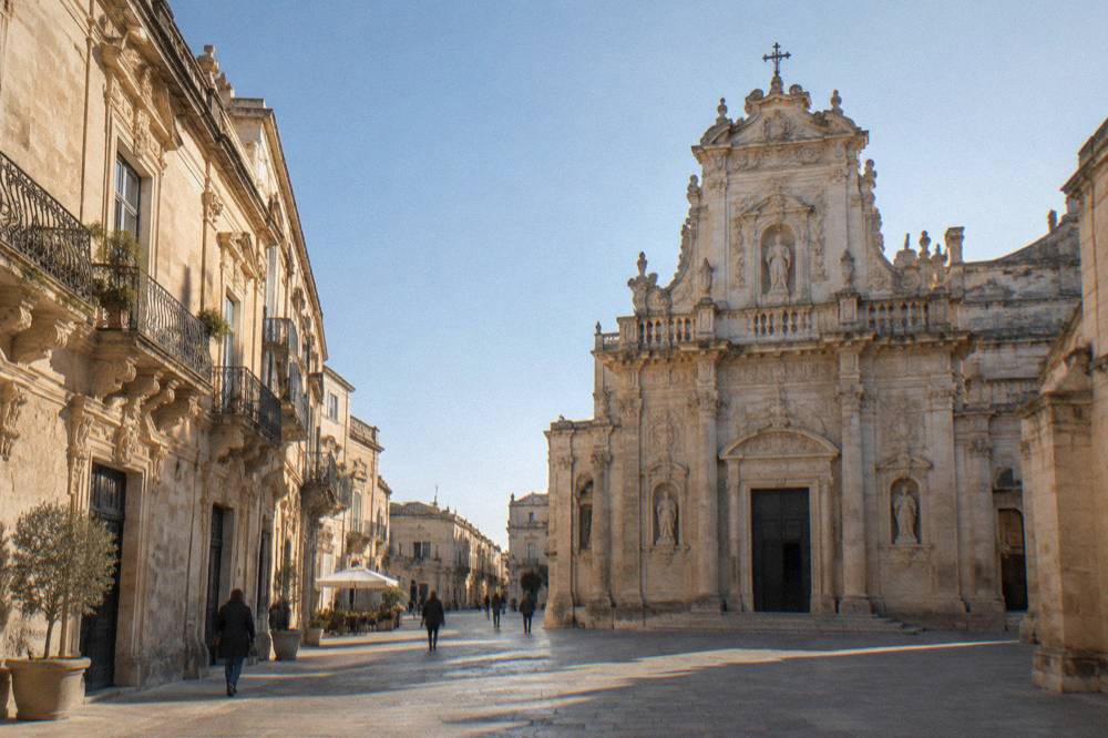An ornate baroque church facade in Lecce carved from pale golden limestone