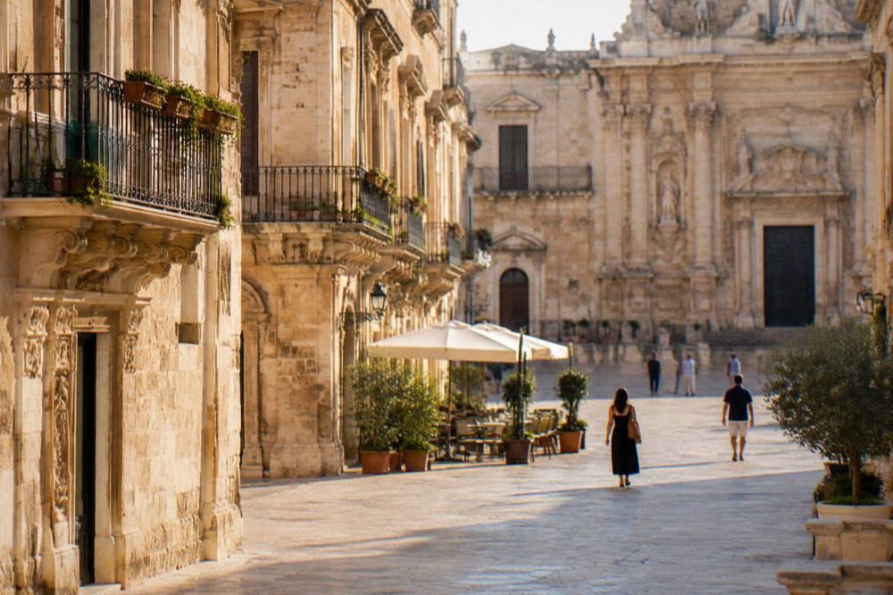 Golden late afternoon light on stone buildings in a southern Italian town square