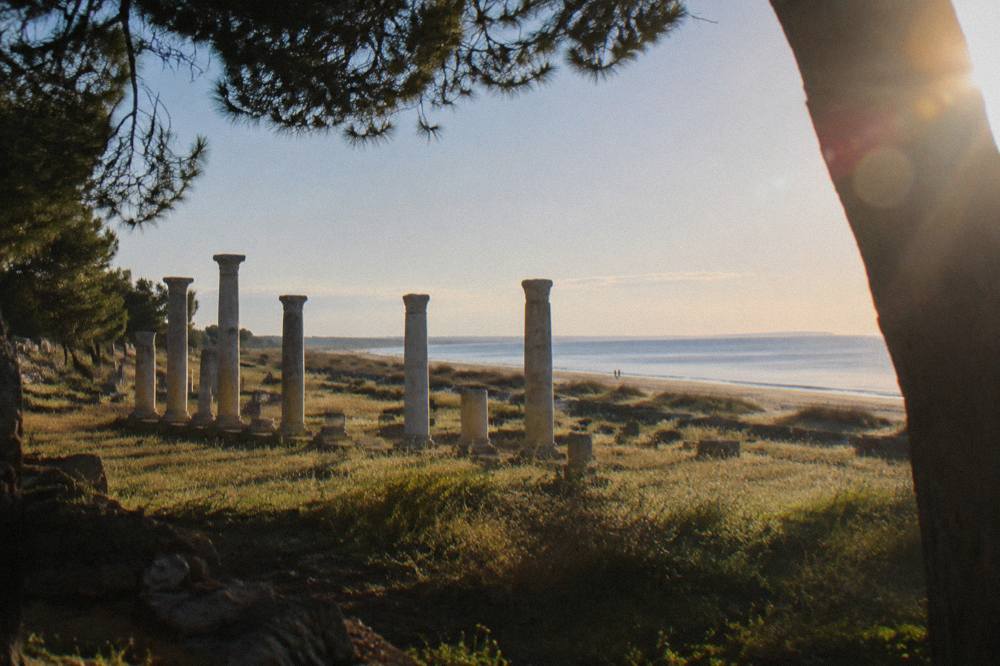 Sandy shoreline along a calm sea with shallow water and distant flat horizon