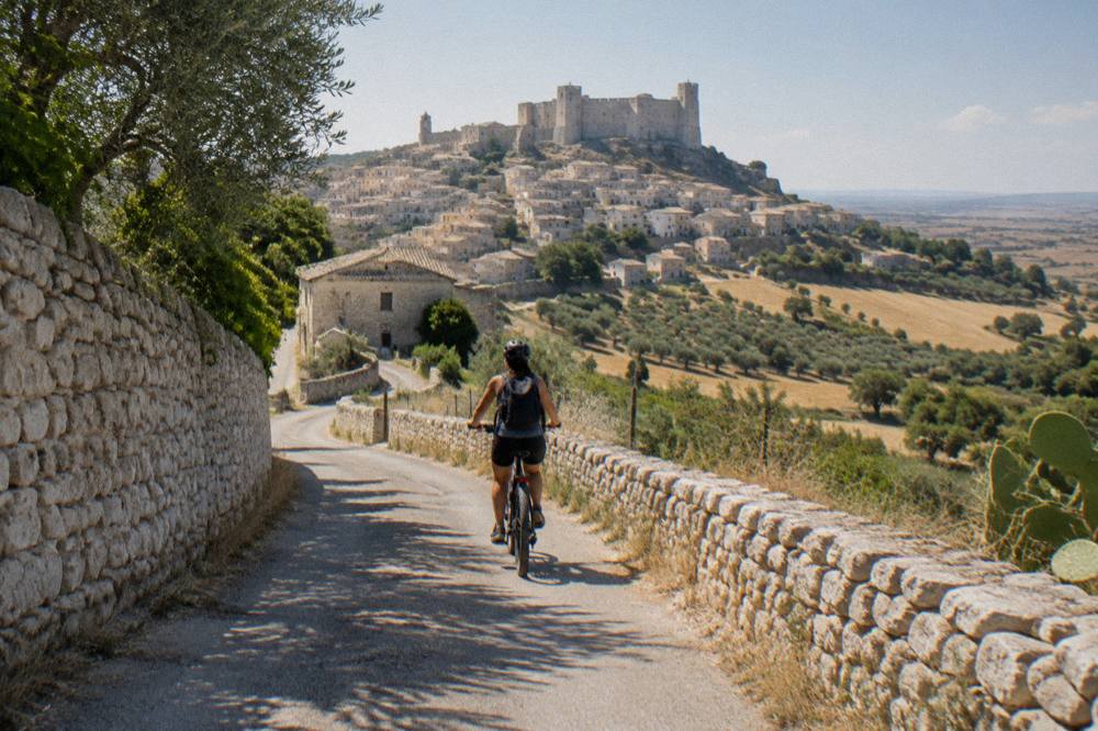 An e-bike rider on a country lane between stone walls in southern Italy