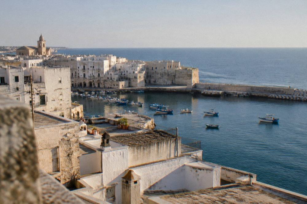 Aerial view of Monopoli's old town rooftops meeting the blue Adriatic sea