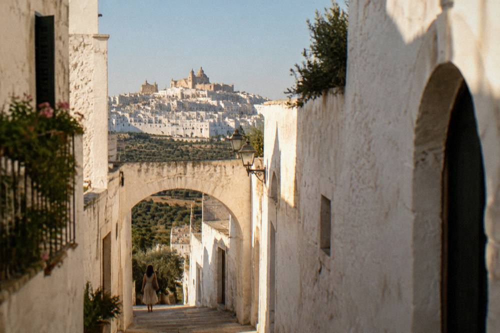 Narrow whitewashed lane with an arched doorway and blue sky above