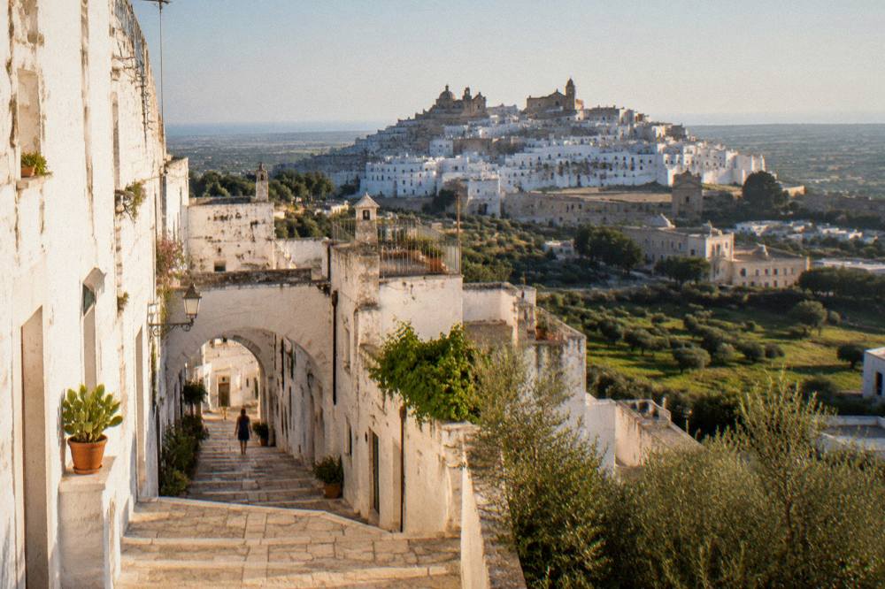 A hilltop white town glowing in late afternoon light above the plain