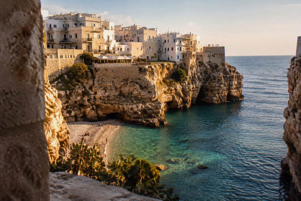 White cliffside buildings above a small sandy cove on the Adriatic coast