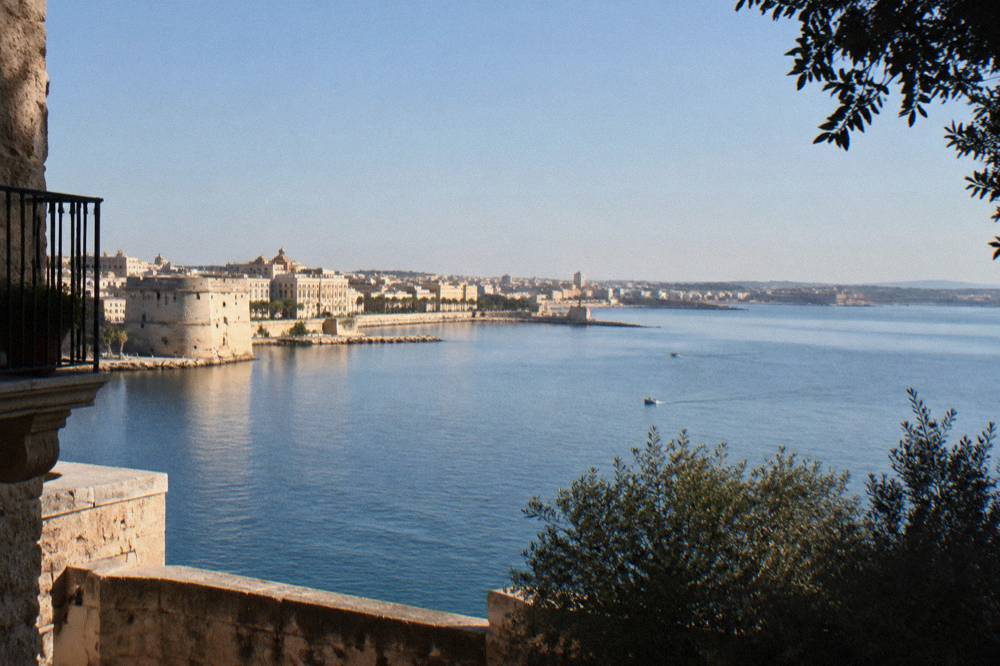 Wide view over the bay of Taranto with calm water and distant buildings along the shore