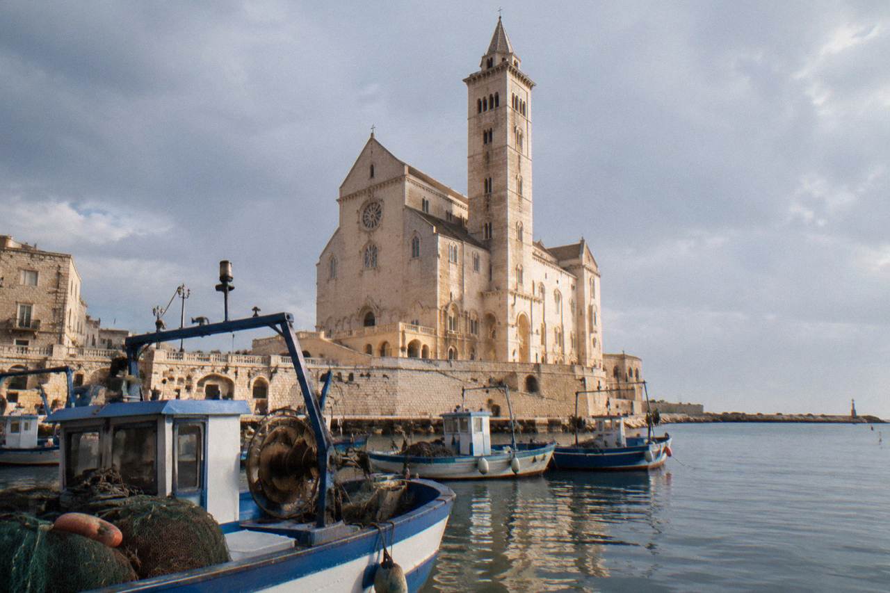 Trani cathedral rising above the Adriatic harbour with fishing boats in the foreground