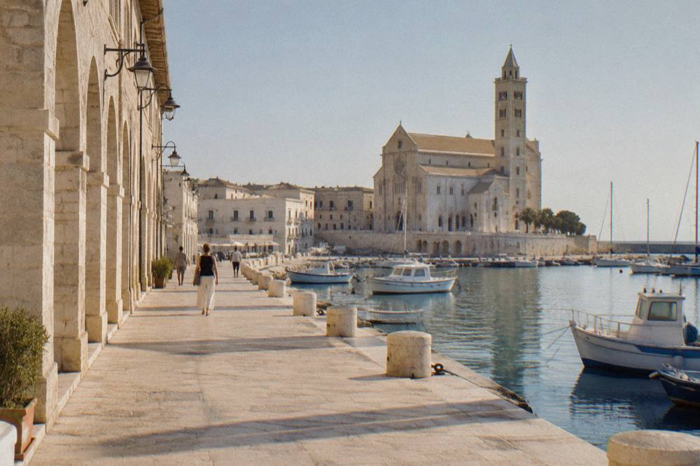 Pale stone arcades along Trani's seafront promenade at midday
