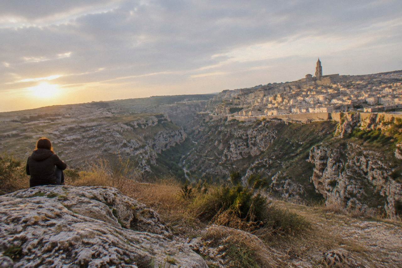 Pale stone cave dwellings of the Sassi district rising above the Gravina canyon at golden hour