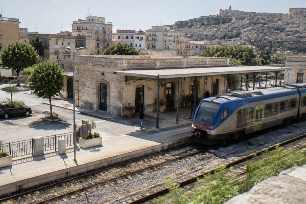A regional train waiting at a small southern Italian station platform