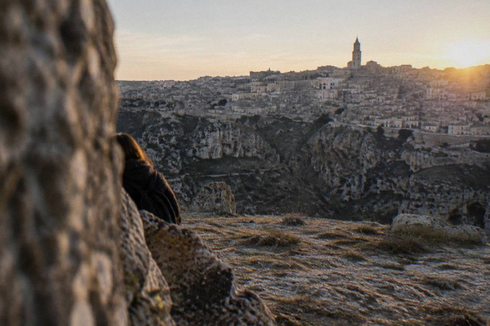 View from the Murgia plateau across the canyon toward the stacked Sassi rooftops at sunset