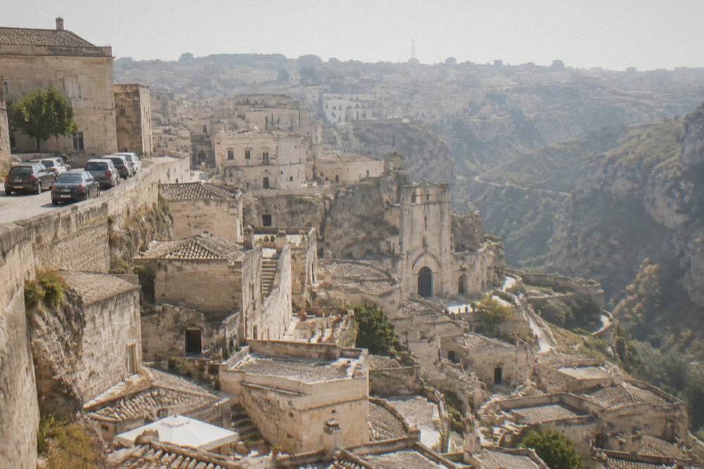 Cars parked on a street above the rooftops of Matera old town