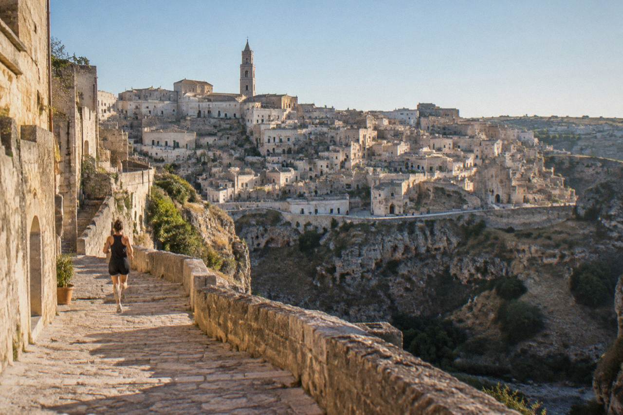 The pale cave city of Matera seen from across the Gravina canyon under a clear sky