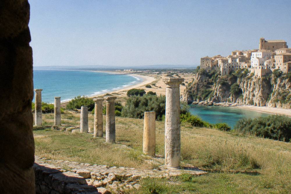 A cliffside old town above a small cove beach with turquoise water on the Adriatic coast