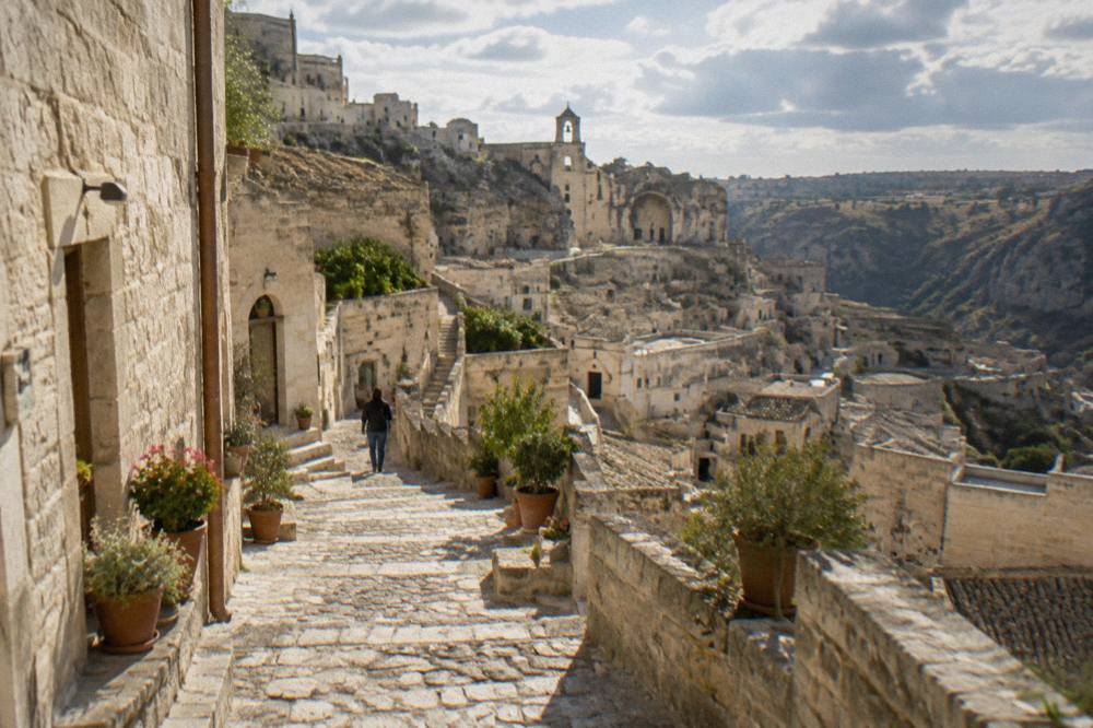 A stone stepped lane in the Sassi of Matera with pale tufa walls and potted plants