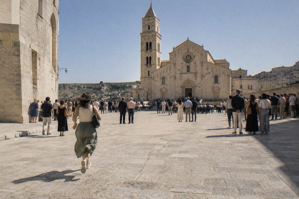 A wide stone square filled with people waiting for an evening event