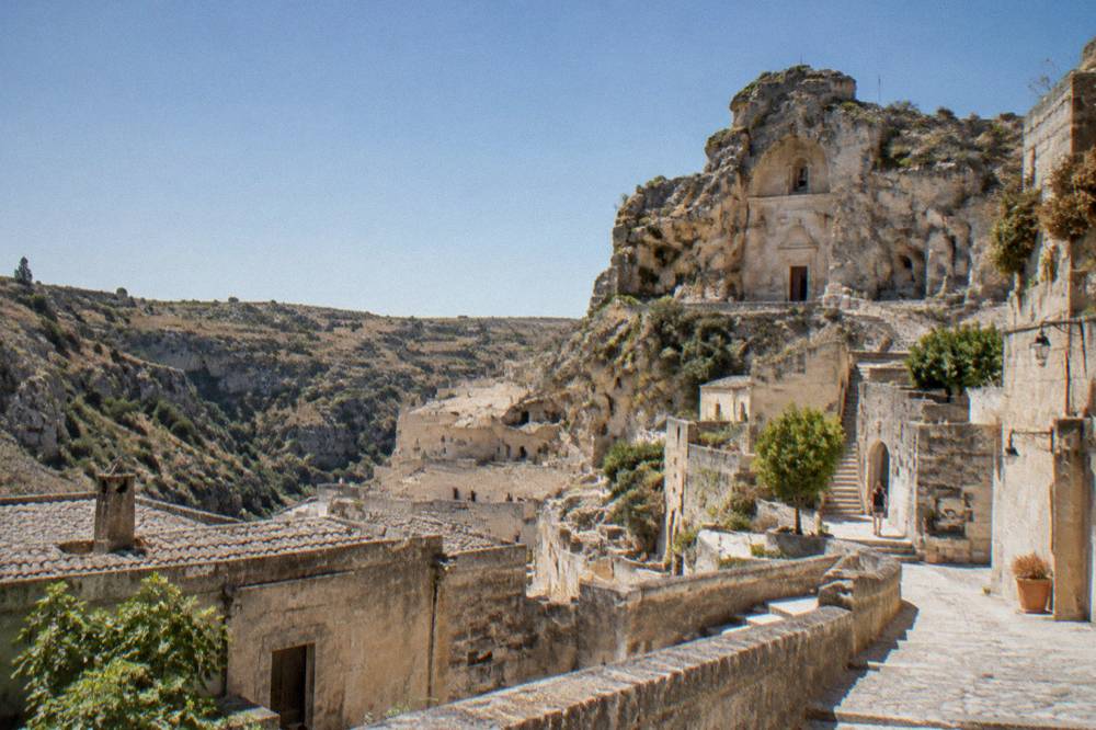 Rock-cut church facade high in a tufa canyon wall above Matera
