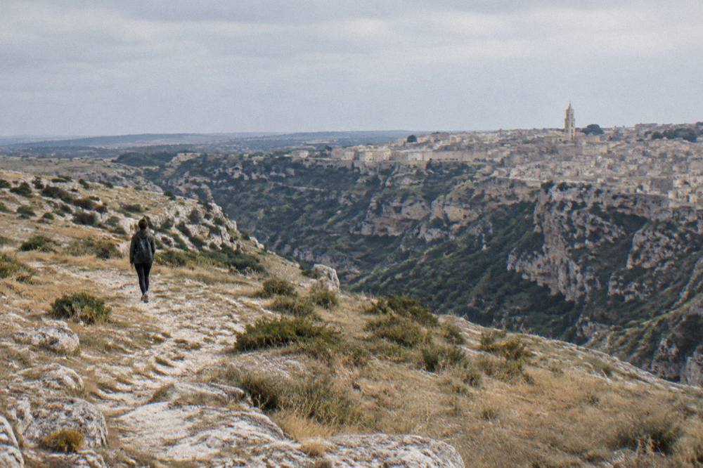 Hiker on a stony trail across the Murgia plateau above the Gravina gorge