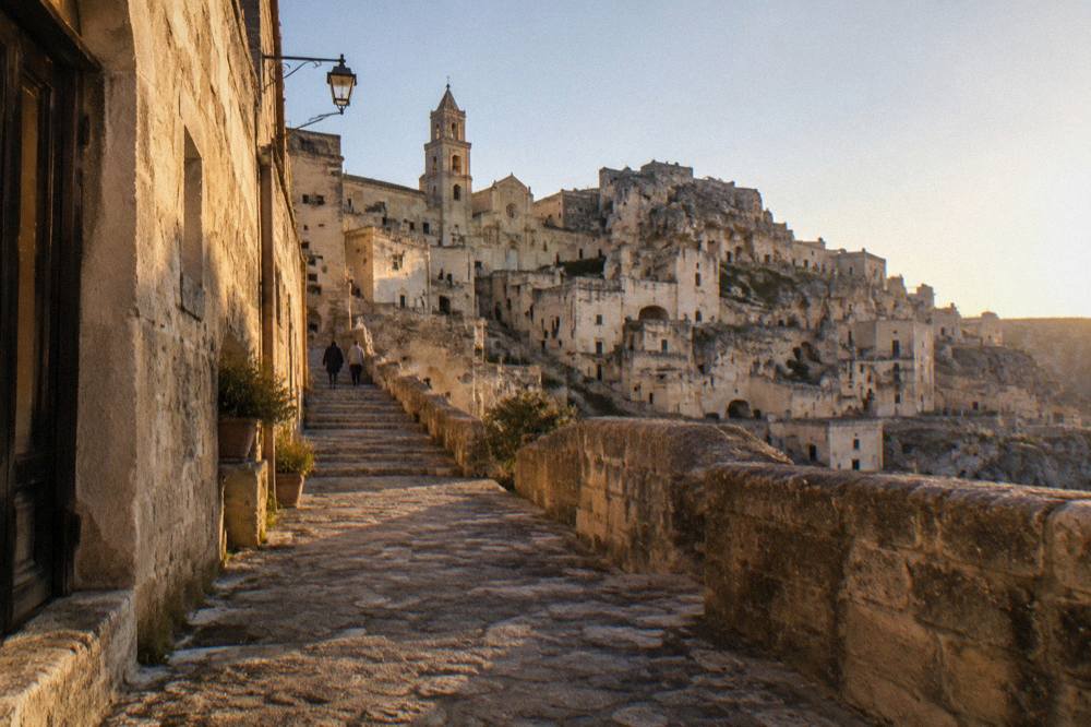 A quiet stone street in Matera at dusk with warm light on the tufa walls