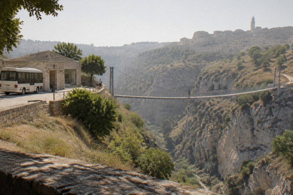 A small shuttle bus parked beside a stone visitor centre on a plateau overlooking a gorge