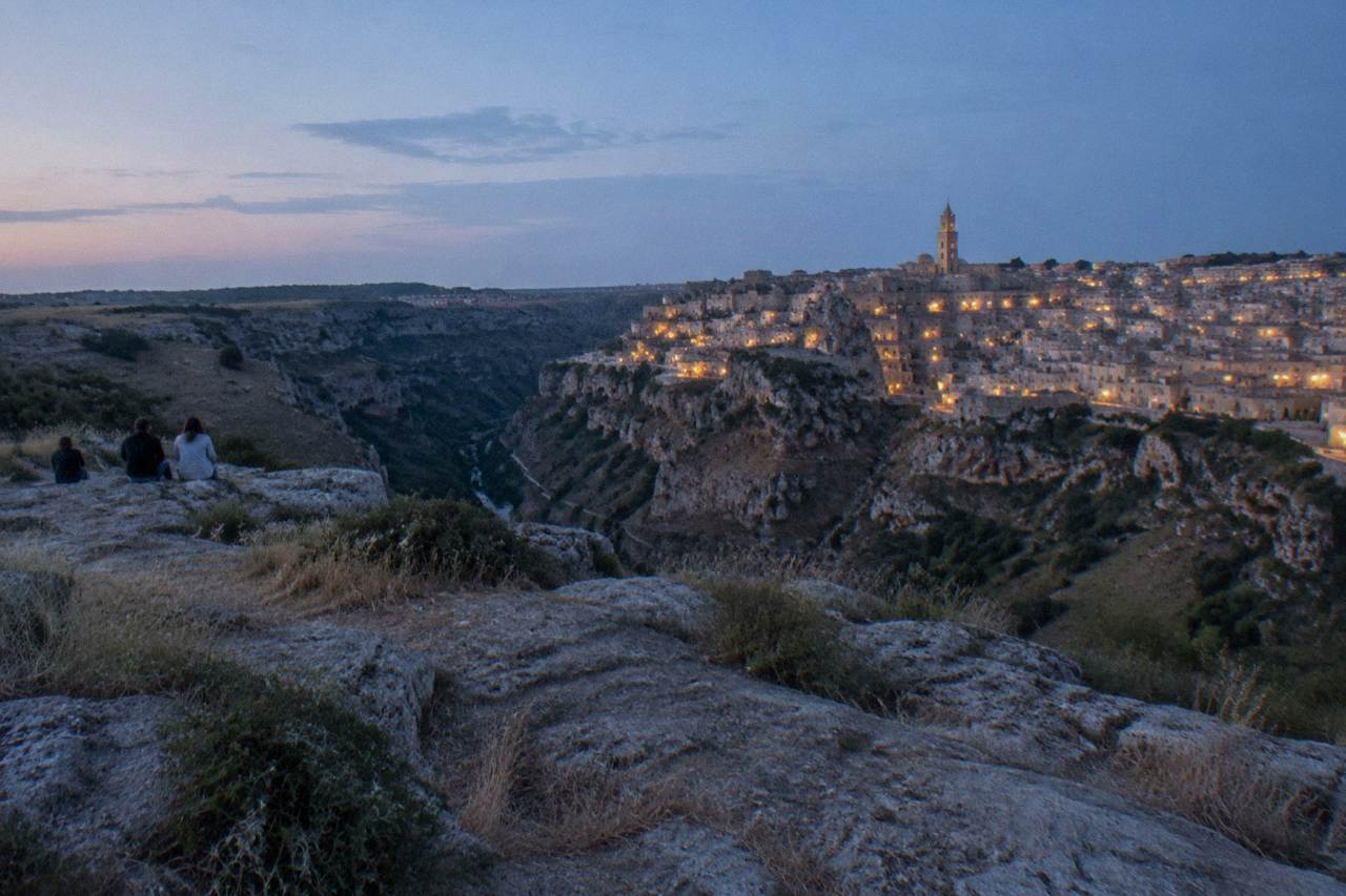 Pale limestone cave dwellings of the Sassi districts stacked above the Gravina canyon at dusk