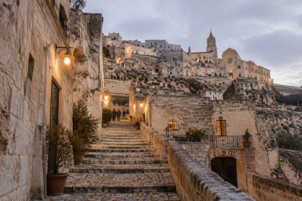 A stone staircase street in the Sassi lit by warm lamps in the evening
