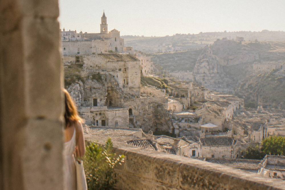 A stone balcony overlooking the layered rooftops of the Sassi at golden hour