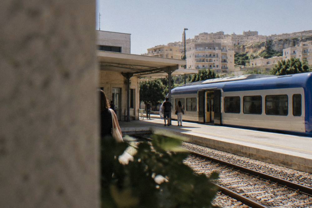 A small regional train waiting at a station platform in southern Italy