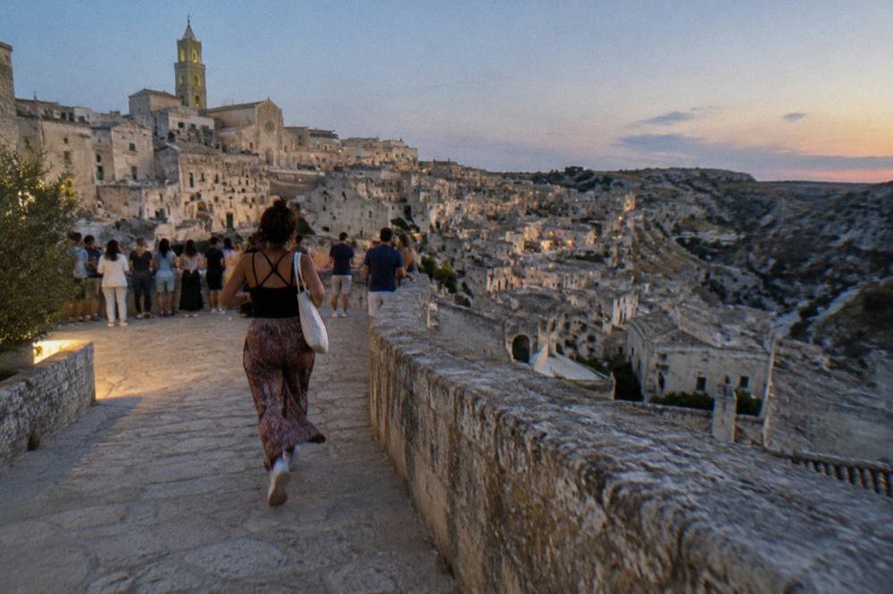 Crowds of visitors on a stone terrace overlooking the Sassi at sunset