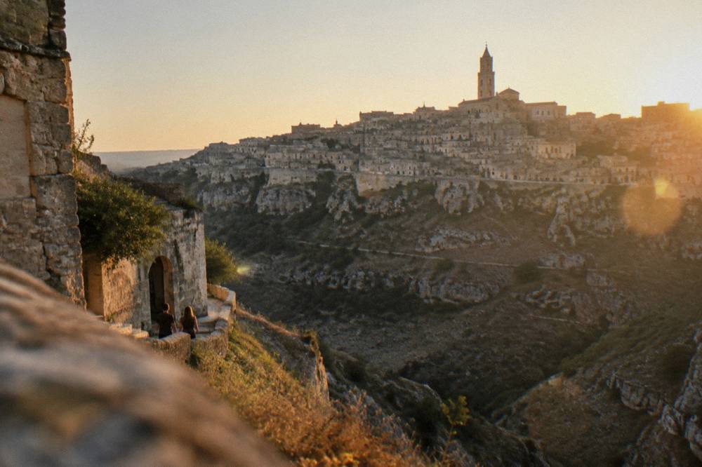 The Sassi skyline of Matera illuminated at dusk seen from across the Gravina canyon