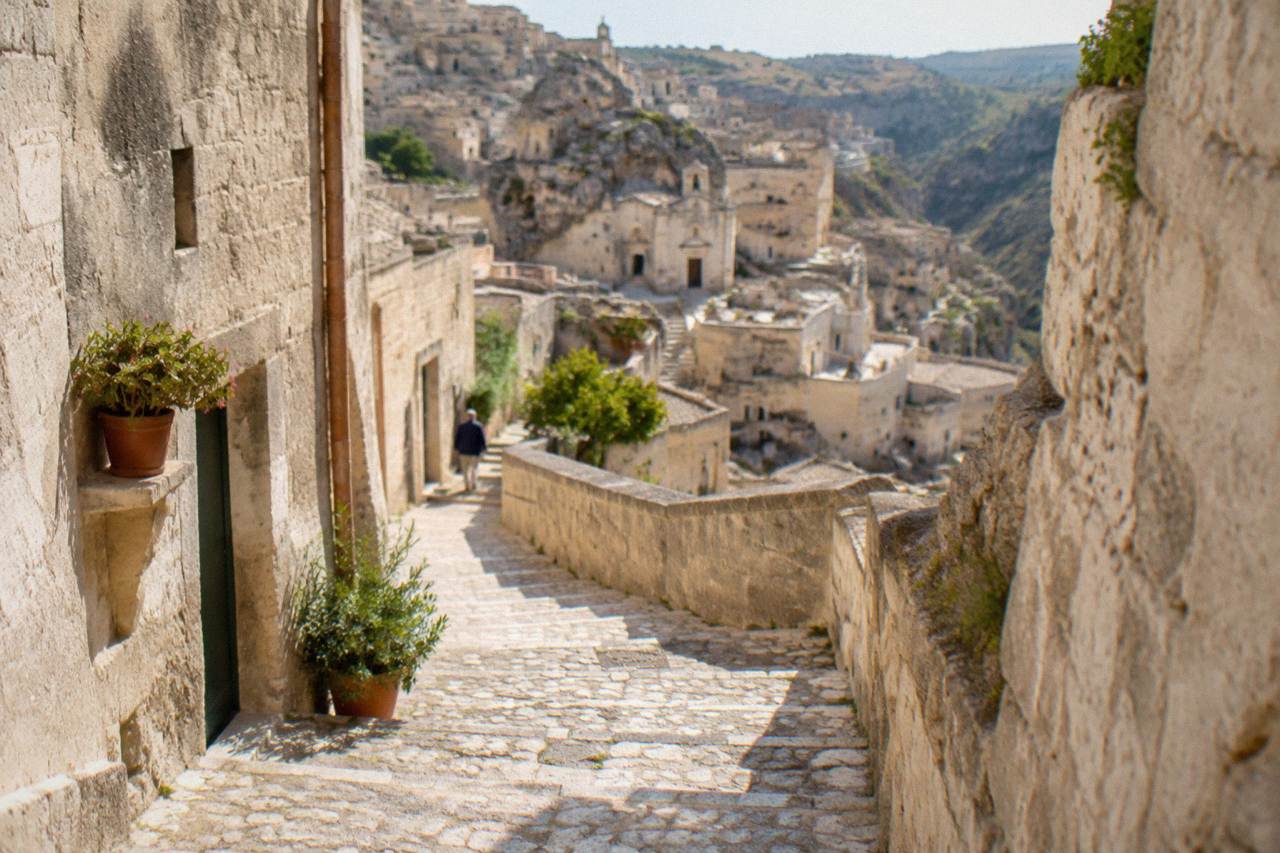 A stone stairway lane in the Sassi of Matera with pale tufa walls rising on both sides