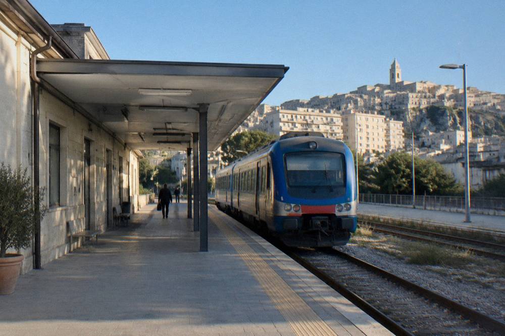 A small regional rail terminus platform with a blue train waiting under morning light