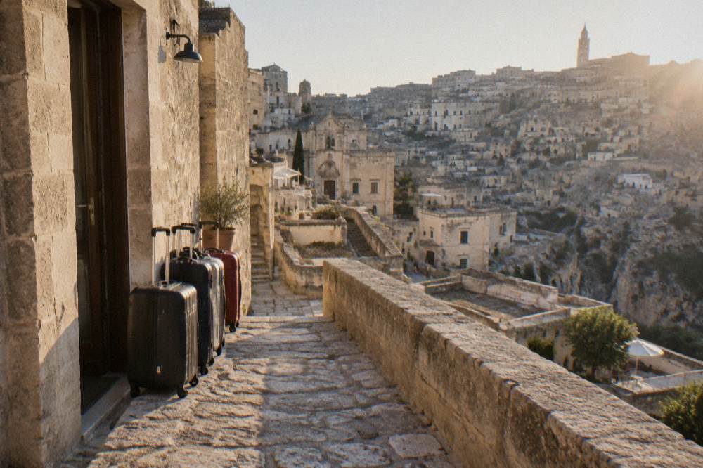 Suitcases lined up against a tufa stone wall beside a hotel doorway in Matera
