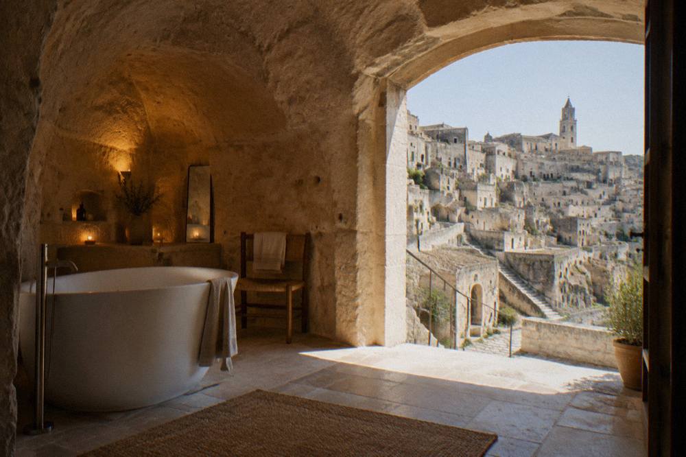 Vaulted stone suite interior with warm lighting and a freestanding bathtub in a converted cave dwelling
