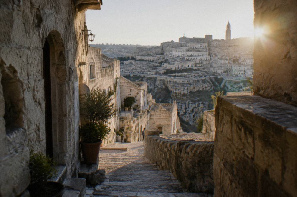A narrow stepped lane of pale stone between old cave dwellings in the Sassi