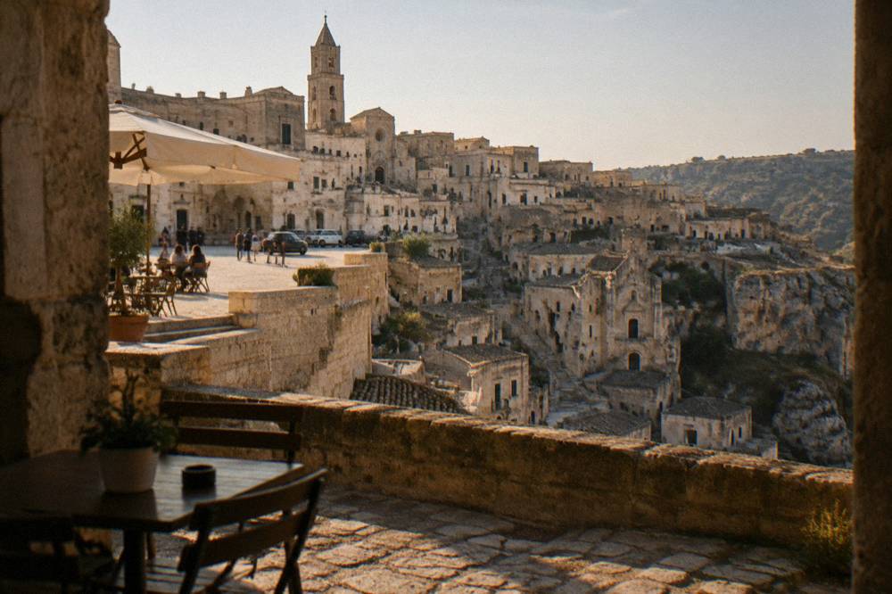 Cars and cafe tables on a flat pedestrian square above the Sassi district